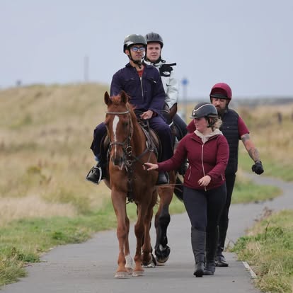 Volunteers leading a dark horse carrying a rider